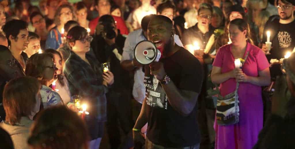 A man talks into a megaphone at an outdoor candlelight vigil