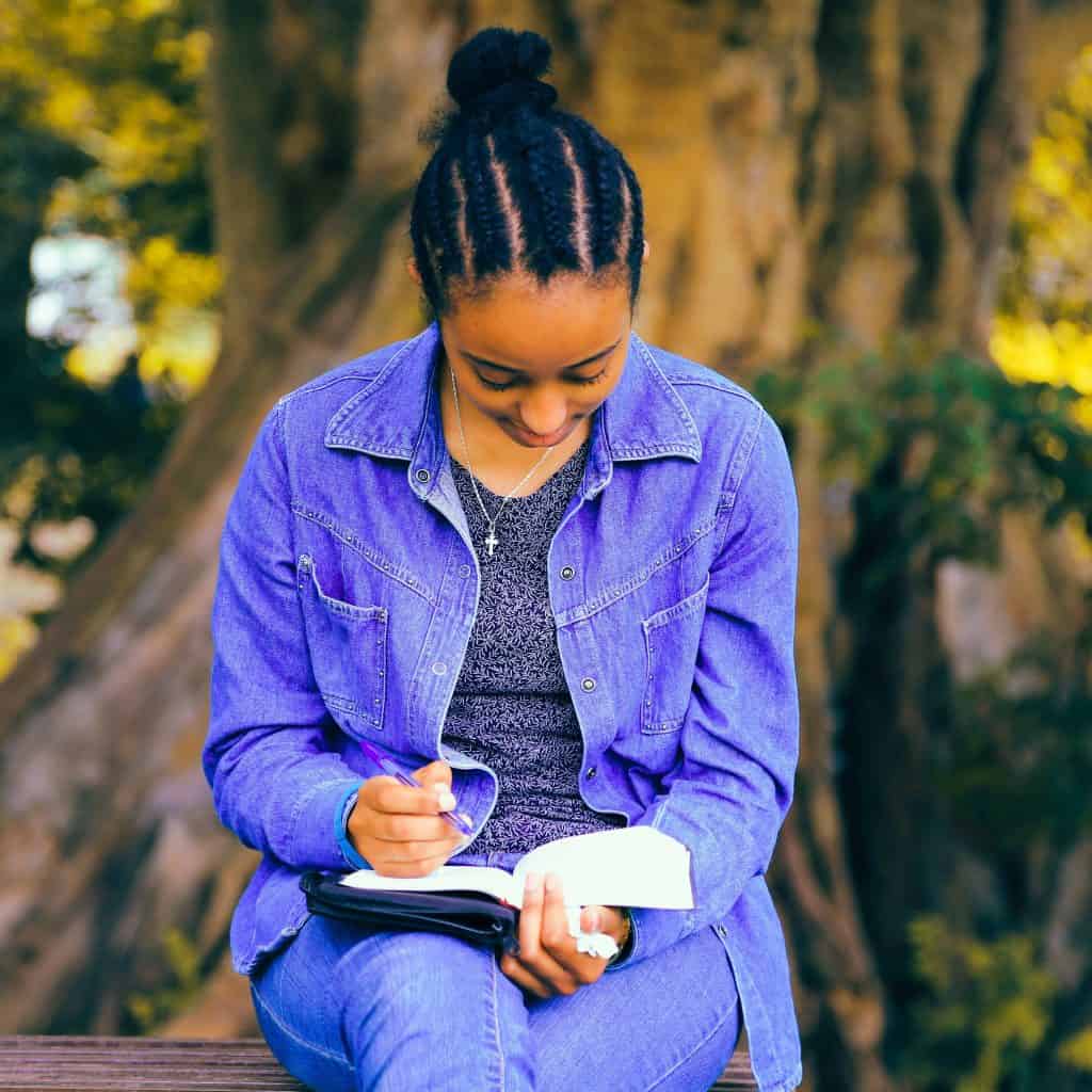 Woman in blue clothes reading on a park bench