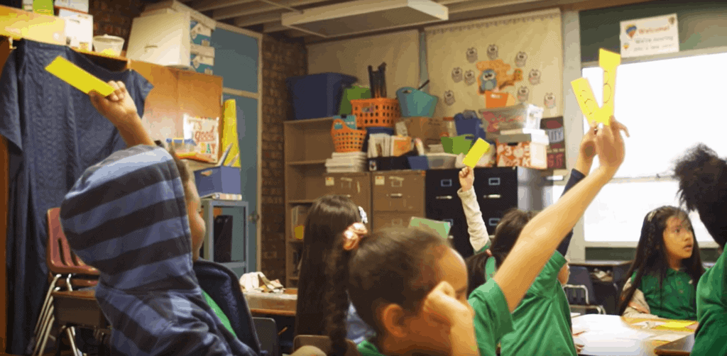 Elementary school students hold up flashcards in class