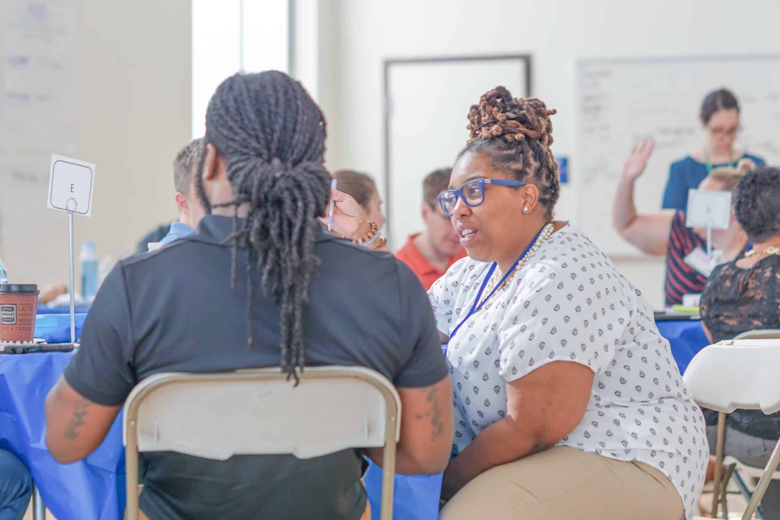 Two DC educators talk to each other during a session