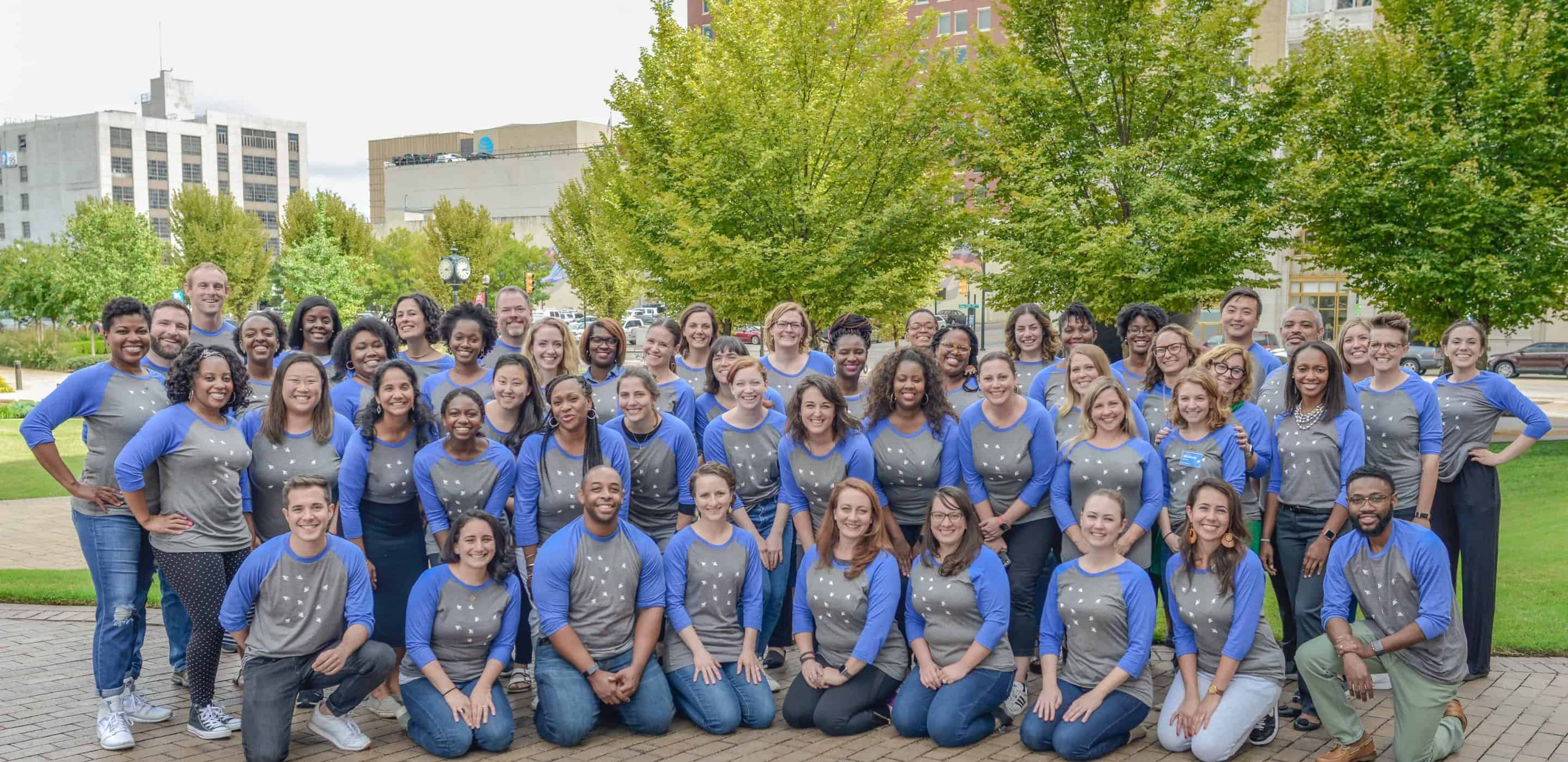 A group photo of the Leading Educators team wearing matching shirts outdoors.