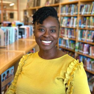 headshot of LaKimbre Brown in a library wearing a yellow shirt