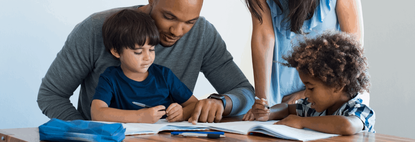 A mom an dad help two boys with homework at a table