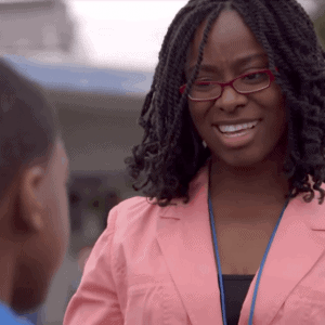 LaKimbre Brown, wearing a pink blazer, talks to a student on the playground