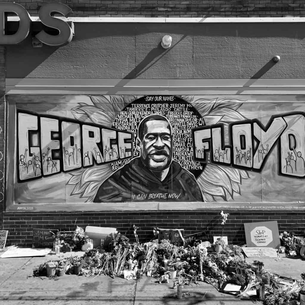 a mural memorial to George Floyd with flowers piled in front