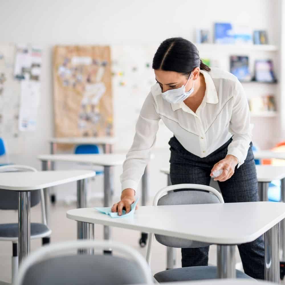 a teacher wipes down a desk