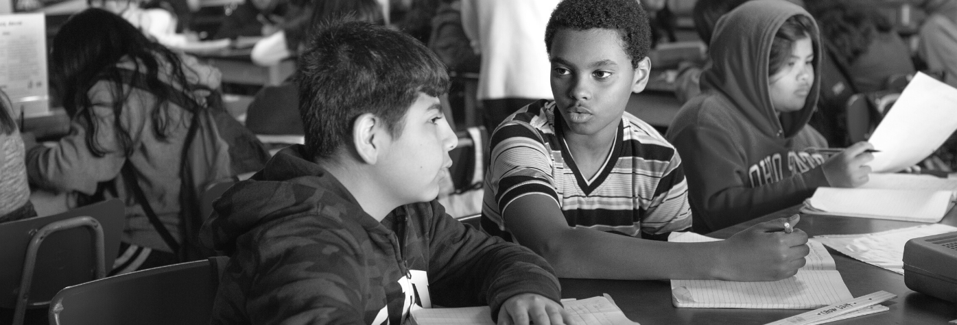 two students discuss a math problem at their desks