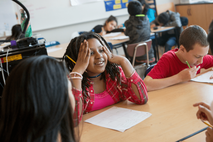 a middle school girl explains a math problem to her teacher