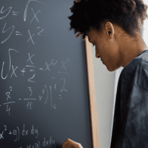 boy doing a math equation on a blackboard